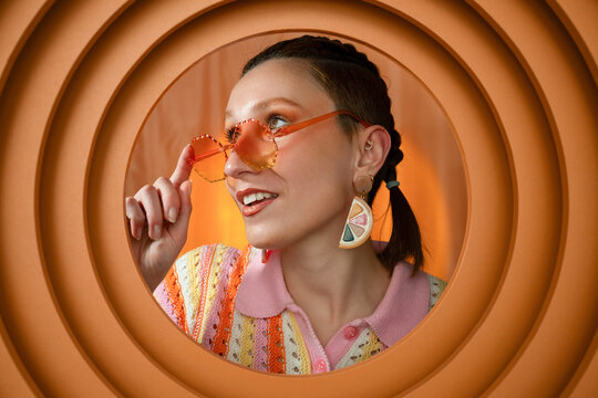 Smiling woman with braids and orange sunglasses in retro fashion style