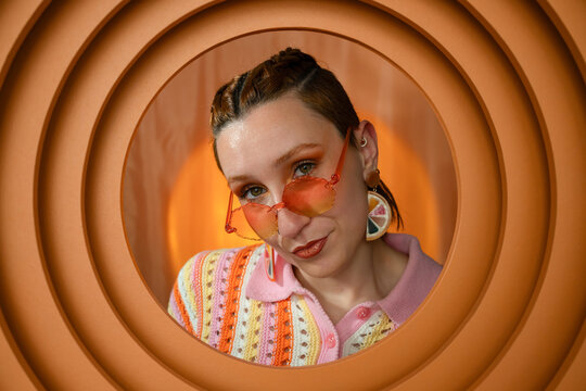 Portrait of fashionable woman in sunglasses and knitwear with orange background