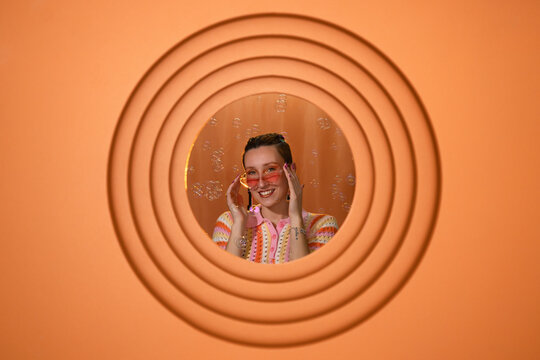 Playful woman with sunglasses and bubbles on orange retro background