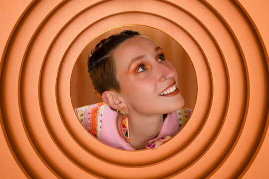 Smiling woman with short hair wearing fashion earring in orange circle