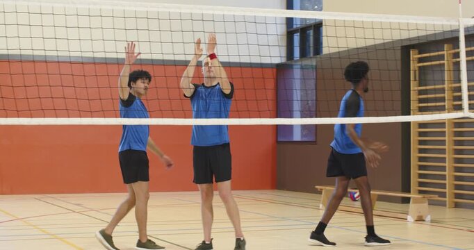 Point ending sending three male blue team players in gym walking to net, shaking, preparing defense
