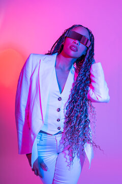 Woman in white blazer with braids posing in studio with VR glasses
