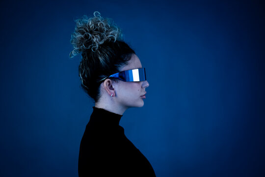 Woman with curly hair wearing AR glasses in a studio setting
