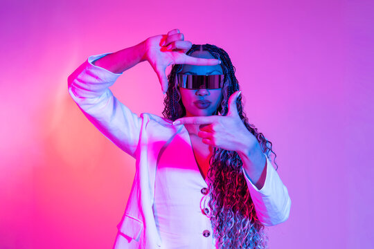 Woman posing with AR VR glasses in white blazer under colored lights