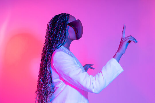 Woman in white blazer with VR glasses interacting in a futuristic studio