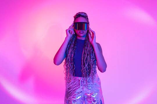 Woman wearing AR VR glasses posing in neon studio
