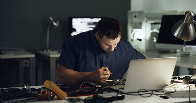 Tools, man and laptop repair in office for hardware diagnostics, measure voltage or troubleshooting. Night, technician and multimeter probe on circuit board for continuity test, broken traces and IT