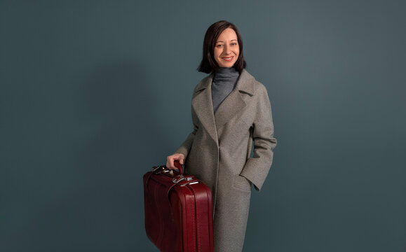Businesswoman with vintage briefcase smiling against gray background