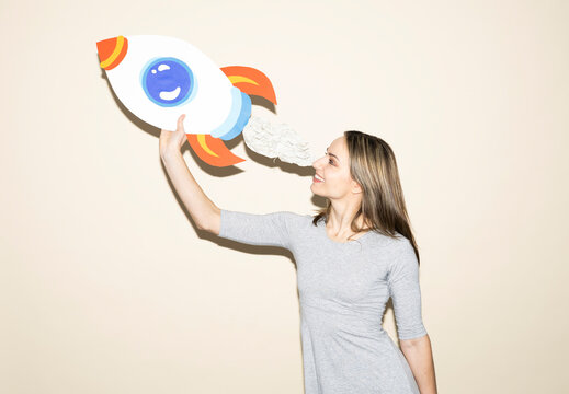 Woman holding handmade paper rocket symbolizing ambition and success