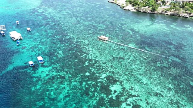 Drone following shot of an outrigger boat near Alona Beach, close-up dynamic angles, Philippines