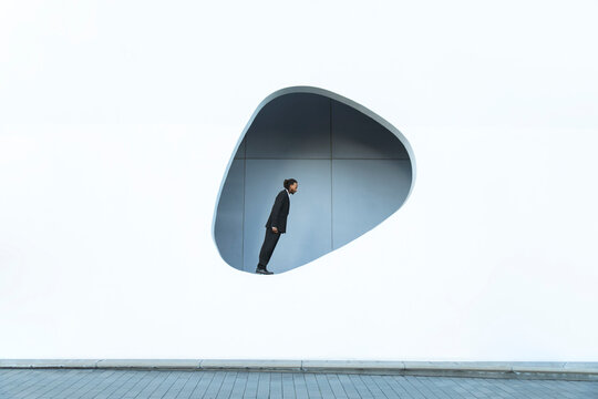 Man in suit leaning forward dynamically in modern Barcelona architecture