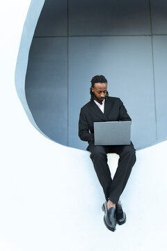 Businessman in formal suit working on laptop outdoors in Barcelona
