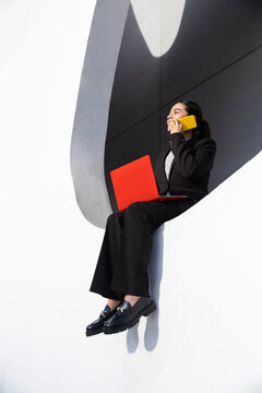 Businesswoman multitasking with phone and laptop outdoors in Barcelona