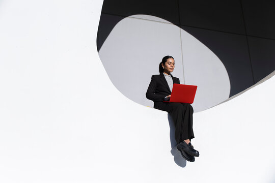 Businesswoman working with red laptop on white circle in Barcelona