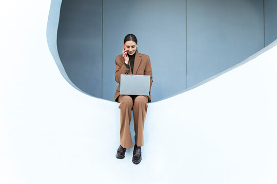 Businesswoman multitasking with laptop and phone call in Barcelona office