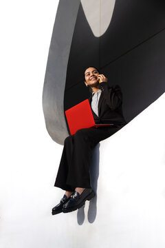Businesswoman multitasking with red laptop and smartphone in Barcelona
