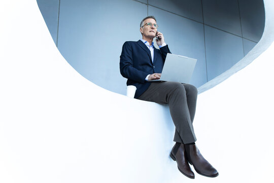 Business professional multitasking outdoors in Barcelona with laptop and coffee