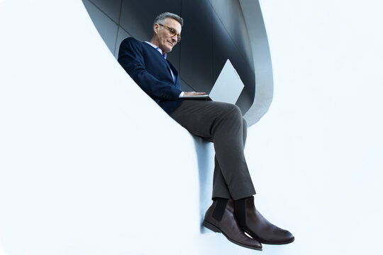 Business professional working with laptop in white circle window Barcelona