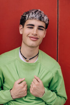 Portrait of cheerful young man in green sweater against red wall