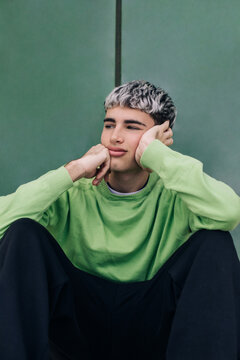 Contemplative man sitting against colored background in relaxed mood