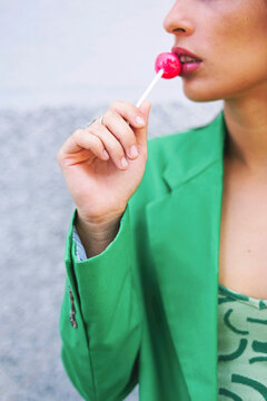 Fashionable woman in green suit holding red lollipop outdoors