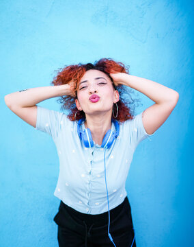 Redhead with headphones enjoying music against blue wall