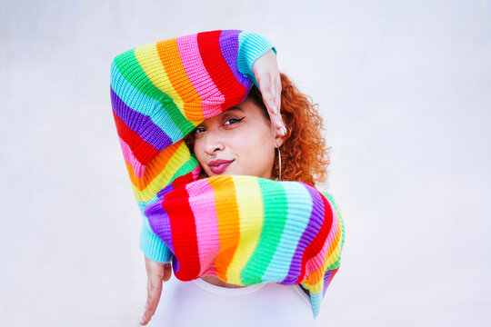 Redhead woman in rainbow sweater striking dancer pose outdoors