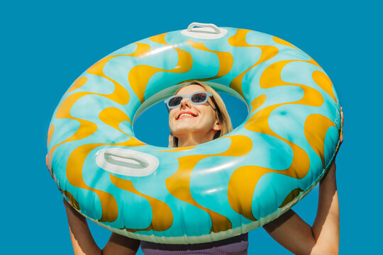 Happy woman with inflatable ring smiling outdoors on summer beach