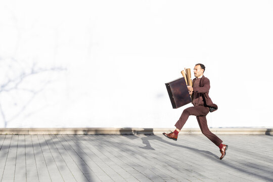 Architect rushing with blueprints outdoors in business attire