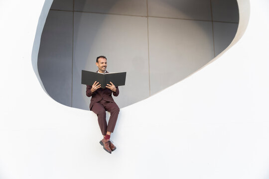 Businessman in suit reading document outdoors demonstrating balance