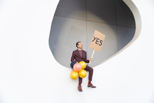 Businessman in suit with yes sign and balloons celebrating success