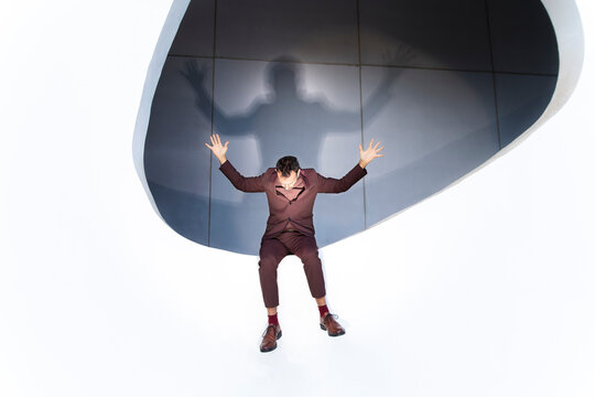 Businessman in suit with hands raised showing stress and crisis