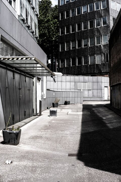 Modern office courtyard alley with concrete surfaces and deep shadow in an urban setting creating empty perspective for conceptual isolation and space