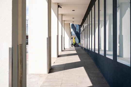 Sunlit corridor walkway with modern columns in an urban office setting showing empty perspective daylight rhythm and clean architecture for circulation