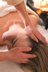 Fototapeta premium Facial massage in cozy spa, therapist hands on client, warm candlelight and salt lamp glow, relaxation ritual, skincare, self care, stress relief, wellness.