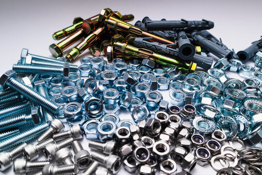 Assortment of metal bolts nuts and anchors on white background, industrial hardware collection