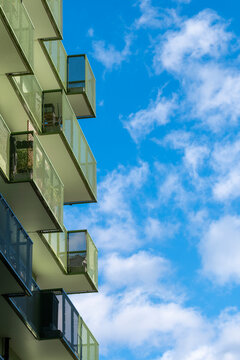 Contemporary residential building with balconies and glass architecture beneath sky clouds in Stockholm captured in daylight for modern urban exterior