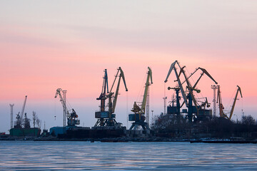 Obraz premium Large container ship docking at busy port with cranes, cargo vessels navigating ocean waters, showcasing maritime shipping and logistics.