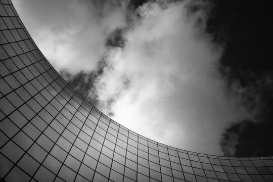 Monochrome abstract facade in modern urban architecture showing curved pattern under sky and cloud with clean contrast geometry for contemporary design background
