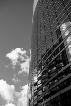 Curved glass skyscraper in monochrome modern architecture as urban reflection meets sky and cloud creating strong contrast lines and abstract design background