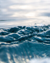 The image captures the tranquil beauty of gentle waves on a serene water surface, reflecting soft light and evoking a sense of peace and relaxation in nature. © Aperezer