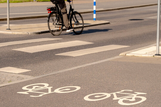 Cyclist on a bicycle crossing a street crosswalk with urban marking and lane layout showing transportation commute safety and traffic awareness