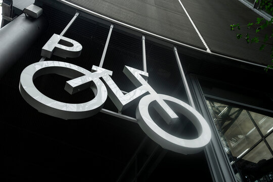 Modern bicycle sign symbol under architecture ceiling in an urban monochrome interior with strong perspective guiding transportation direction