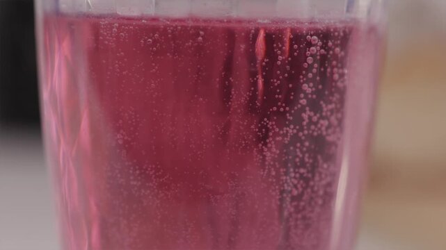 Cinematic tilt up macro of red bubbles and carbonation