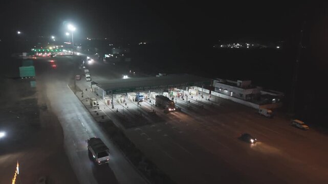 Night toll plaza with traffic lights and vehicles, Highway toll booth aerial view at night, Busy toll plaza with cars and street lights, Night traffic at toll gate on highway stock video.