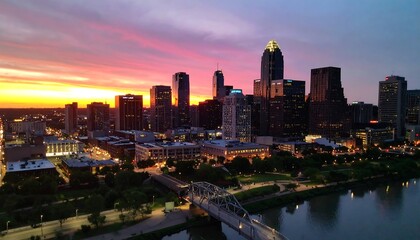 Naklejka premium City Skyline at Sunset with River and Bridge in Foreground