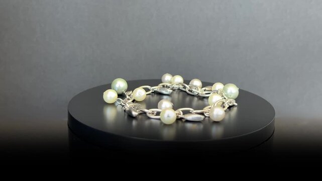 Pulsera de perlas multicolor girando 360 grados sobre base negra