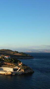 Aerial view of a scenic coastal amphitheater and traditional buildings by the blue sea in Paralio Astros, Greece, under a clear sky.