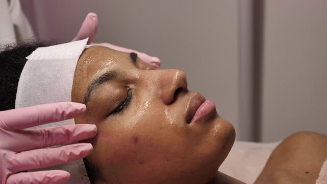 A Black woman receiving a professional facial treatment during Black History Month. Concept of inclusive beauty, self-love, and Juneteenth wellness
