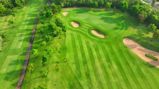 Drone aerial view of a manicured golf course with sand pits and scattered trees, emphasizing sustainability, green infrastructure, and outdoor wellness in contemporary lifestyles.
